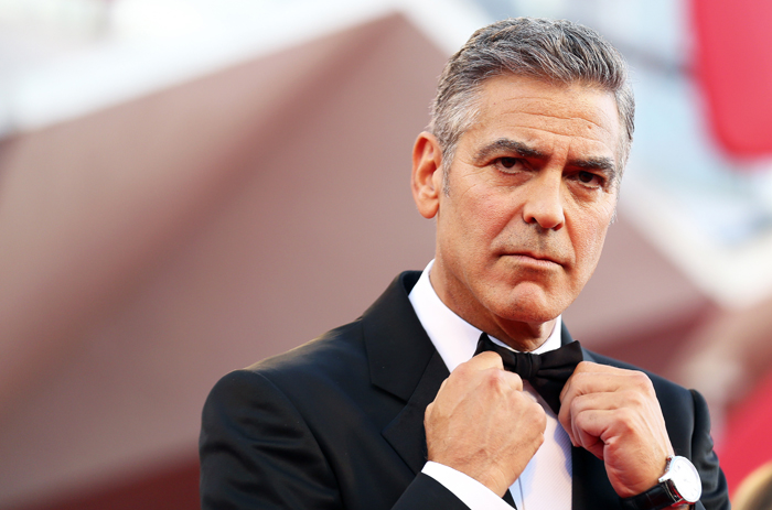 U.S. actor Clooney adjusts his bowtie as he arrives on the red carpet for the premiere of "Gravity" at the 70th Venice Film Festival