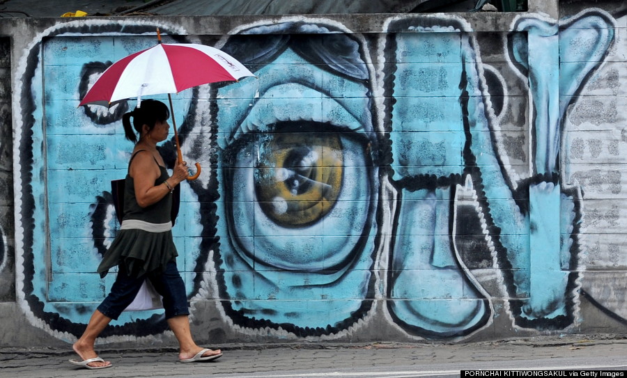 A woman walks past a wall showing graffiti paintings in Bangkok on July 14, 2010.  AFP PHOTO/PORNCHAI KITTIWONGSAKUL (Photo credit should read PORNCHAI KITTIWONGSAKUL/AFP/Getty Images)