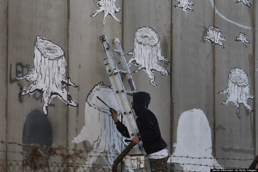 BETHLEHEM, WEST BANK - DECEMBER 05:  The Italian street artist Blu paints graffiti on Israel's separation barrier December 5, 2007 where is cuts a path into the biblical West Bank city of Bethlehem. Dozens of large-scale artworks by various artists, along with some by elusive British artist Banksy, are part of an exhibition called Santa's Ghetto.  (Photo by David Silverman/Getty Images)