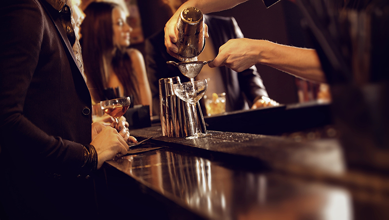 Bartender using a shaker and pouring wine into the wine glass