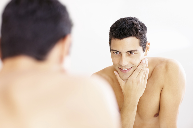 Reflection of a young man in the bathroom mirror after shaving