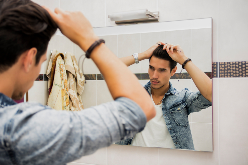 Reflection of Young Man Bushing Hair in Mirror Getting Ready to Go Out